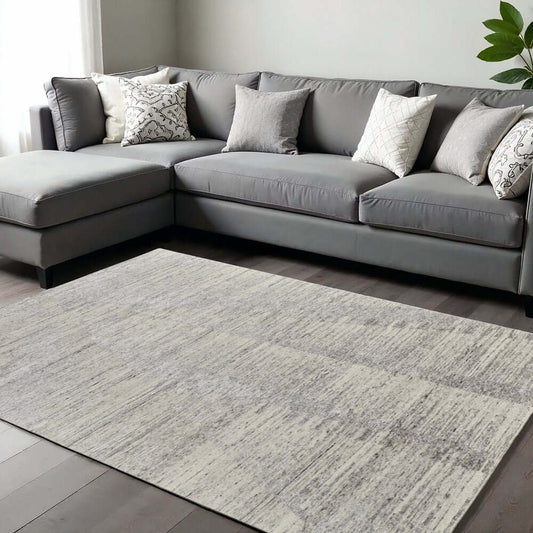 9' X 13' Ivory And Gray Abstract Hand Knotted Distressed Area Rug in cozy living room setting with sectional couch.
