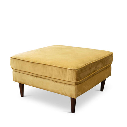 The Amber MCM Square Upholstered Ottoman 32 by Ashcroft Furniture features a square, mustard yellow cushioned top and dark wooden legs in Mid-Century Modern style, shown against a white background.