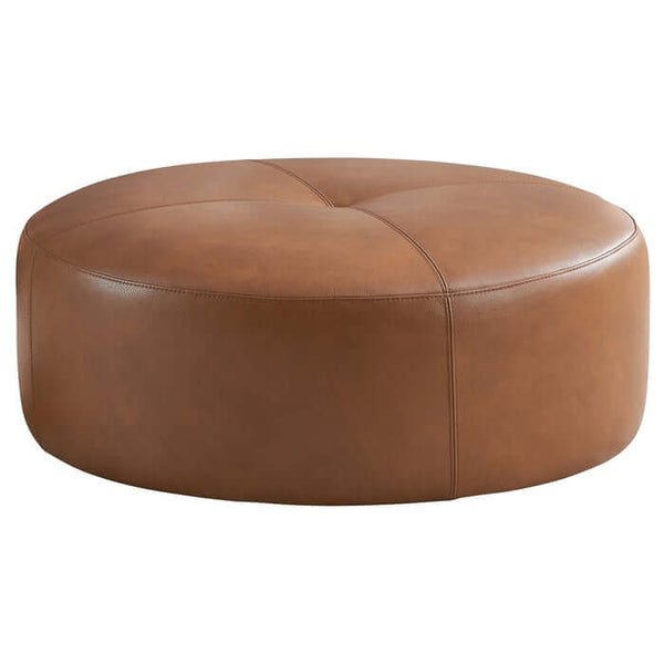 The Ashcroft Furniture Co. Rochelin Round Tan Leather Ottoman 36 features smooth, cushioned genuine leather upholstery with subtle stitched seams, showcasing mid-century modern style against a plain white background.