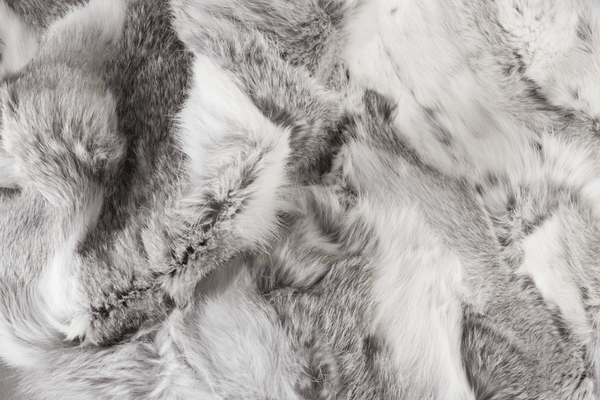 The Home Roots Gray Rabbit Fur Throw Blanket features plush gray and white fur on one side and smooth solid gray fabric on the other, offering a luxurious touch to any space.