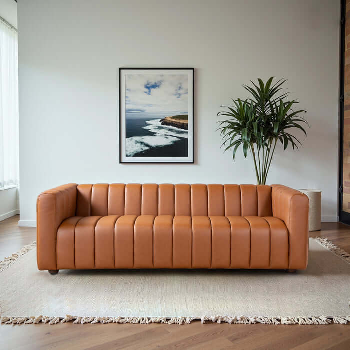 Elrosa Channel Tufted Cognac Faux Leather Sofa in a stylish living room setting with modern decor.