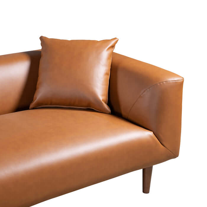 Close-up of Elwood MCM cognac brown PU leather sofa with accent pillow, showcasing its sleek design and premium upholstery.