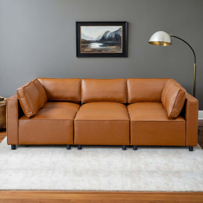 Reno Cognac PU Leather Modular Sofa Sectional in modern living room setting with elegant floor lamp and artwork.