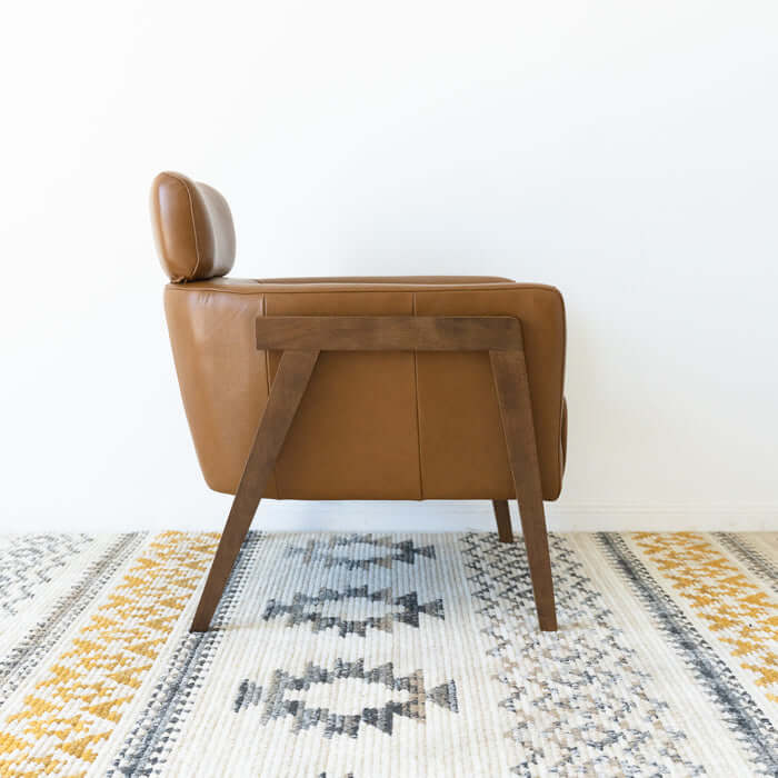 Kayson MCM tan leather lounge chair side view on a patterned rug, showcasing mid-century modern design and comfort.