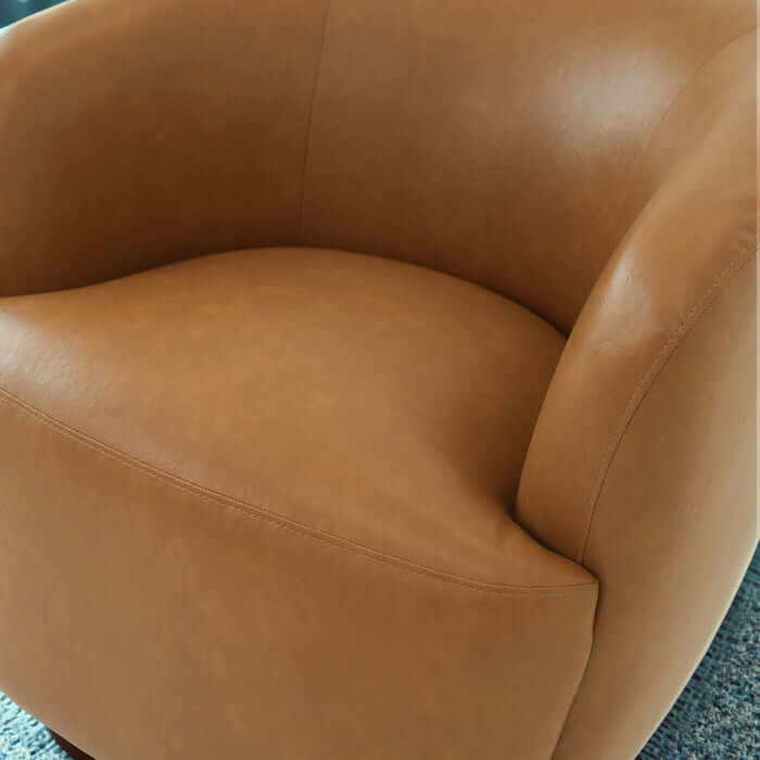 Close-up of Mina Tan Vegan Leather Swivel Barrel Chair showcasing soft tan leather and curvy design.