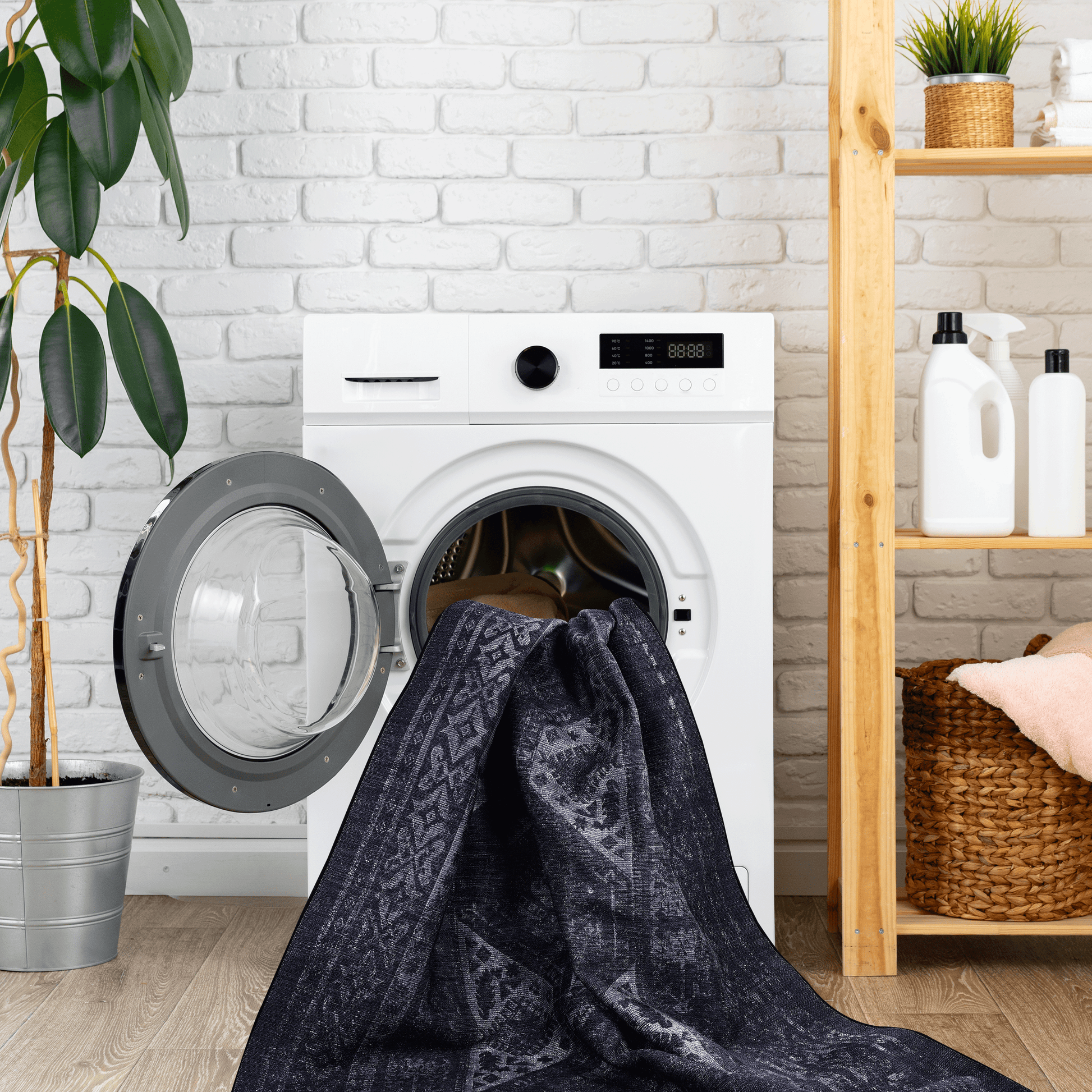 Black area rug being washed in a modern front-load washing machine, set in a stylish laundry room.