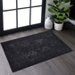 Black and gray washable rectangular area rug in a modern living space with a plant and window.