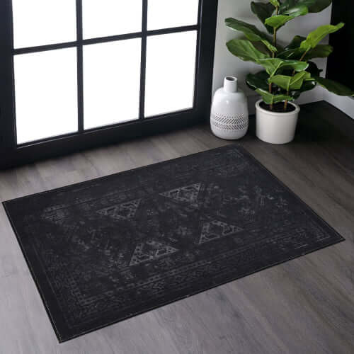 Black and gray washable rectangular area rug in a modern living space with a plant and window.