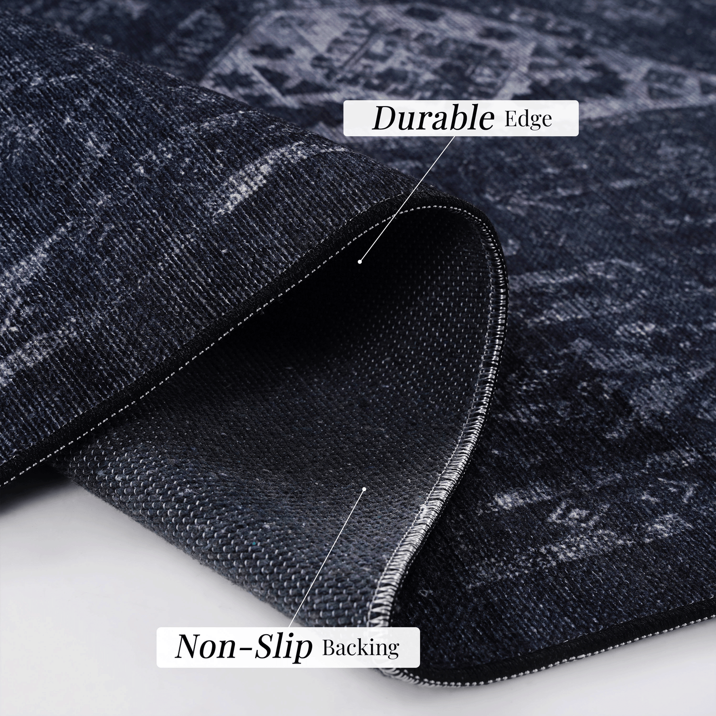Close-up of black and gray area rug showing durable edge and non-slip backing features.