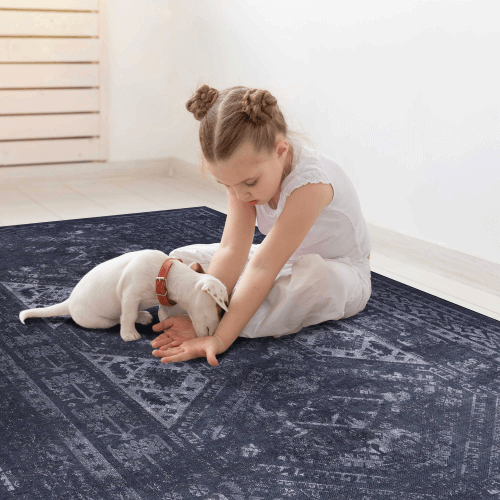 Child playing with puppy on a black and gray washable area rug in cozy living space.