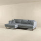 The Ashcroft Furniture Blake Velvet Upholstered L-Shape Chaise Sofa Sectional 107 with wooden legs and cushions sits in a minimal empty room, its reversible chaise set against a plain beige wall and floor.