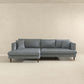 The Ashcroft Furniture Blake Velvet Upholstered L-Shape Chaise Sofa Sectional 107 features plush velvet, wooden legs, and matching cushions, arranged against a beige wall in a minimalist room.