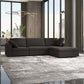 Modern living room with the Ashcroft Furniture Cecilia Dark Gray Modular Chaise Sofa Sectional 121, a reversible chaise, on a gray rug, floor-to-ceiling windows, city view, and minimalist decor with a plant, sleek light fixture, and floor lamp.