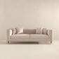 The Ashcroft Furniture Edward MCM Elegant Tufted Velvet Sofa 90 in beige, with four matching cushions, sits against a plain light wall and floor in a minimalist room.