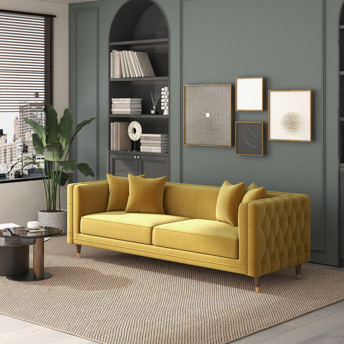 Modern living room with Ashcroft Furnitures Edward MCM Elegant Tufted Velvet Sofa 90 in mustard yellow, four matching cushions, textured rug, round coffee tables, wall art, and built-in shelves against a muted green-gray wall.