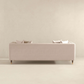 The Ashcroft Furniture Edward MCM Elegant Tufted Velvet Sofa 90 in light beige, featuring velvet upholstery and four matching cushions, is viewed from the back against an off-white wall in a minimalist room.