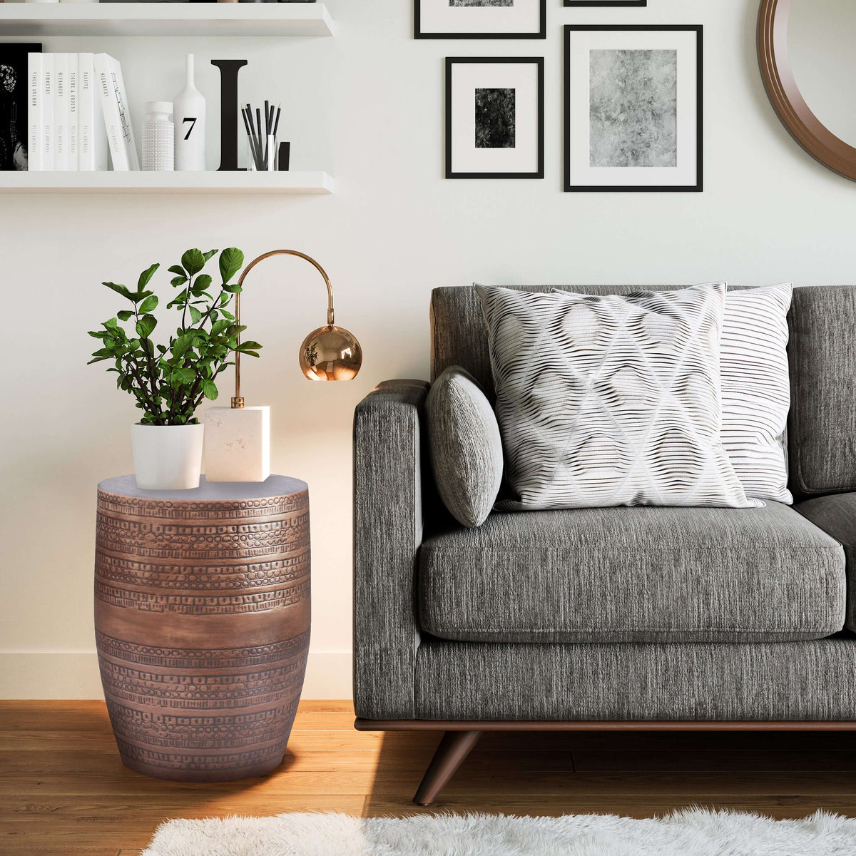 Engraved Antique Copper Round Accent End Table 15W next to a grey couch with decorative pillows and a plant.
