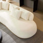 White rounded L-shaped chaise sofa sectional with plush pillows, designed for modern living spaces.