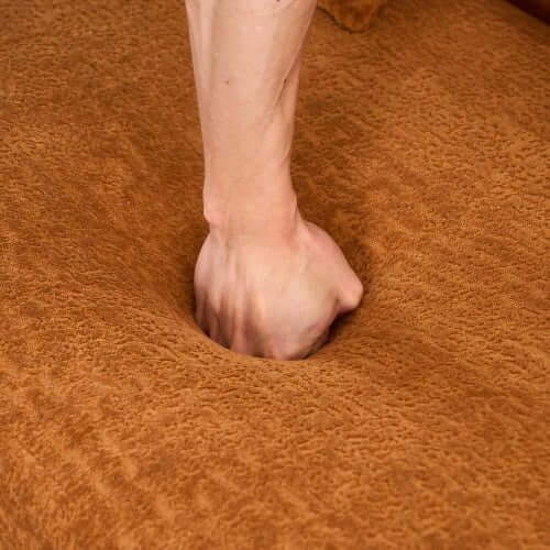 A hand pressing into the soft surface of a chenille sofa fabric, showcasing its plush comfort.