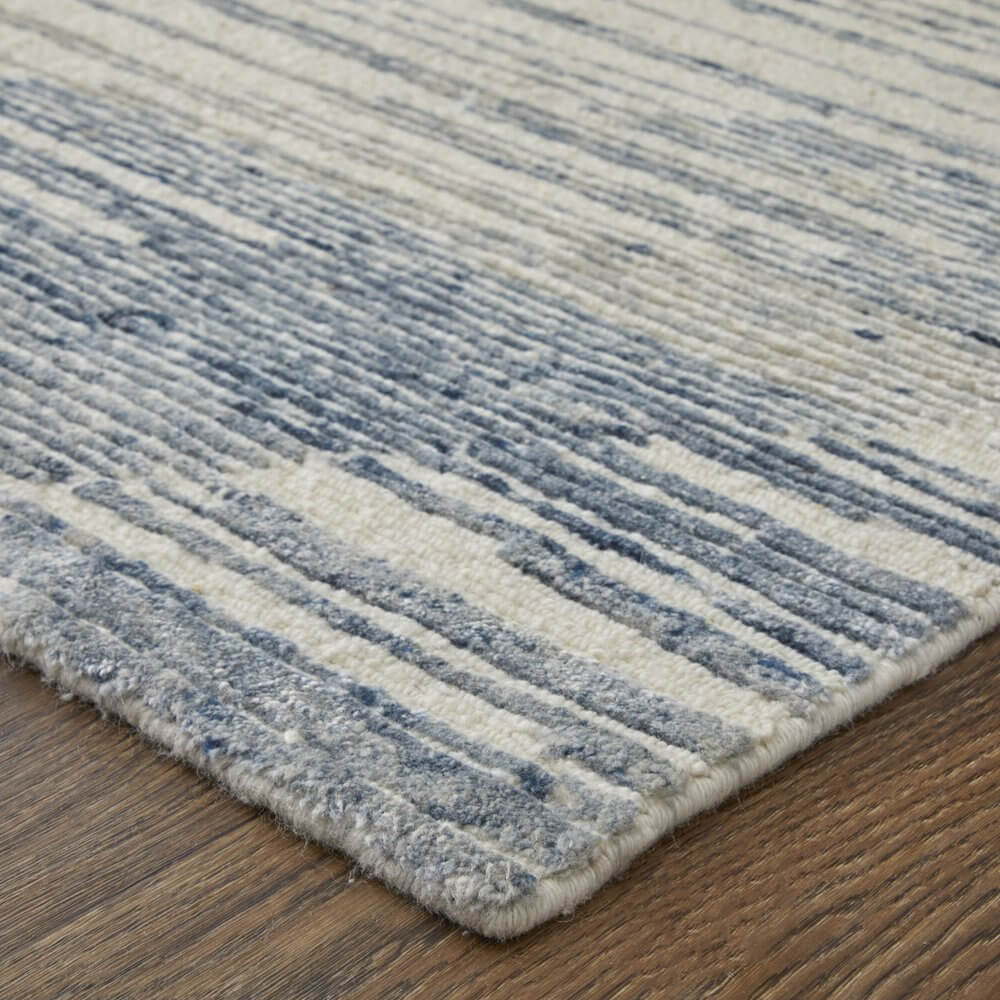 Ivory Blue And Silver Abstract Hand Knotted Distressed Area Rug | 9' x 13' on wooden floor with abstract pattern.