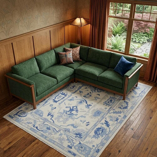 Ivory and Blue Wool Floral Hand Knotted Area Rug With Fringe Area Rug | 9' x 13' under a green sectional sofa in a cozy room.