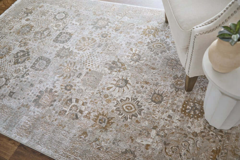 Ivory Gray And Gold Floral Area Rug With Fringe Area Rug | 9' x 13' displayed under a chair.