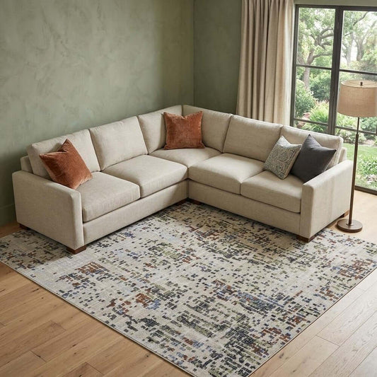 Ivory Green and Blue Abstract Power Loom Area Rug | 9' x 13' under a light-colored sectional sofa in a cozy living room setting.