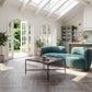 Jamela Teal curved sofa in a bright room with large windows and a coffee table, showcasing modern design and cozy style.