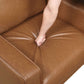 MCM Brown Faux Leather Armchair – Modern Upholstered Accent Chair showing cushioned seat with hand pressing down.