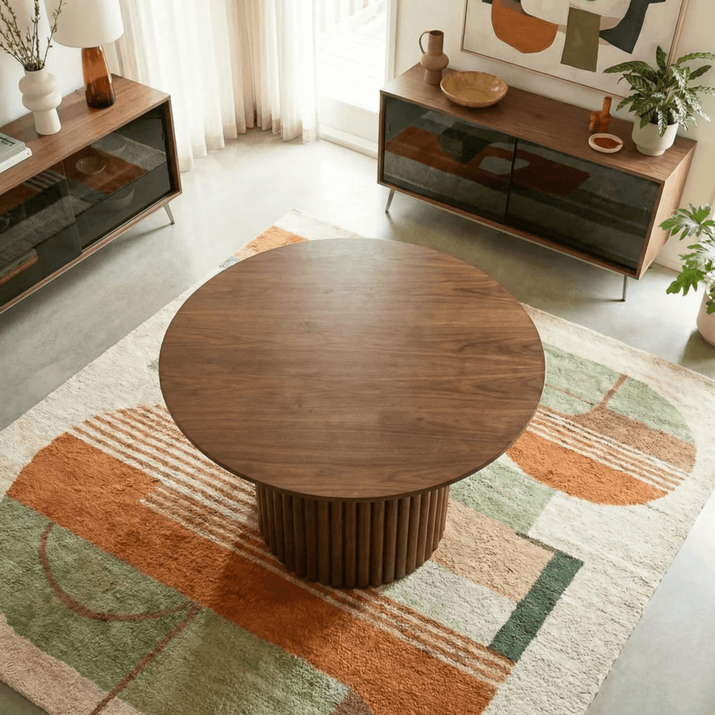 Merlin 35" Solid Wood Round Dining Table in Walnut with Ribbed Pedestal Base on a colorful area rug.