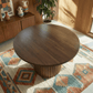 Merlin 35" Solid Wood Round Dining Table in Walnut with Ribbed Pedestal Base on a decorative rug.