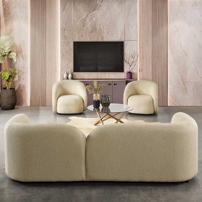 A modern living room featuring the Ashcroft Furniture Donna Minimalist Curved Boucle Sofa 93 in cream, with armchairs, a round glass coffee table, marble walls, minimalist decor, potted plants, and a TV on a built-in cabinet.