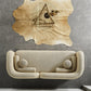 The Donna Minimalist Curved Boucle Sofa 93 by Ashcroft Furniture in beige, accented with round cushions, sits against a gray tiled wall topped by a tan animal hide with geometric triangle and feather artwork.