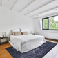 Modern bedroom featuring a cozy double bed and a decorative dark blue area rug.