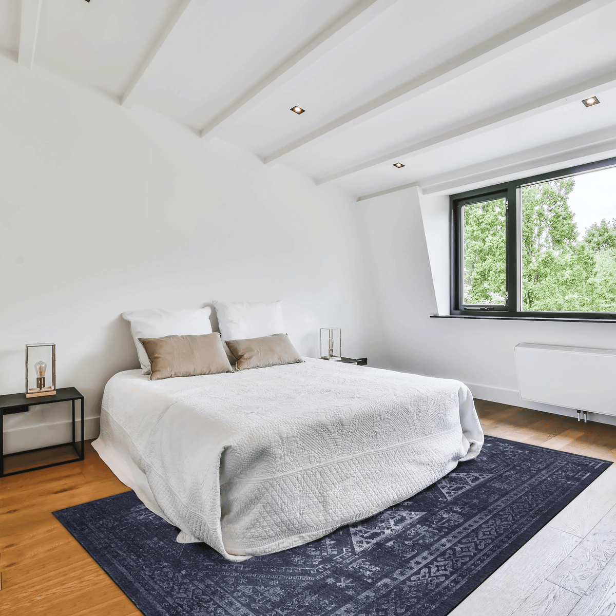 Modern bedroom featuring a cozy double bed and a decorative dark blue area rug.