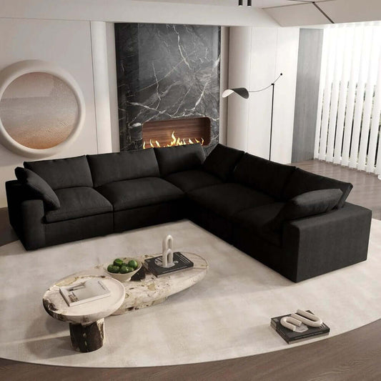 Stylish black modular L shaped sectional in a modern living room with a fireplace and decorative coffee table.