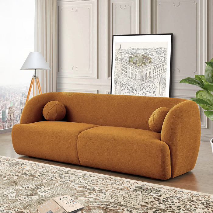 A modern living room showcases minimalist style with the Anna Boucle Fabric Upholstered Sofa 87 by Ashcroft Furniture in mustard, paired with two round cushions, a patterned rug, floor lamp, potted plant, and a framed architectural print against decorative molding.