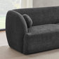 The Anna Boucle Fabric Upholstered Sofa 87 by Ashcroft Furniture, shown in modern dark gray with textured boucle fabric, rounded armrests, and a matching cushion, is placed on a light rug near a large window with sheer white curtains.
