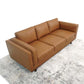 The Ashcroft Furniture Chase MCM Genuine Leather Sofa 91 is a modern brown three-seater with square arms and back cushions, adding luxury to any room atop a light-patterned rug against a white backdrop.