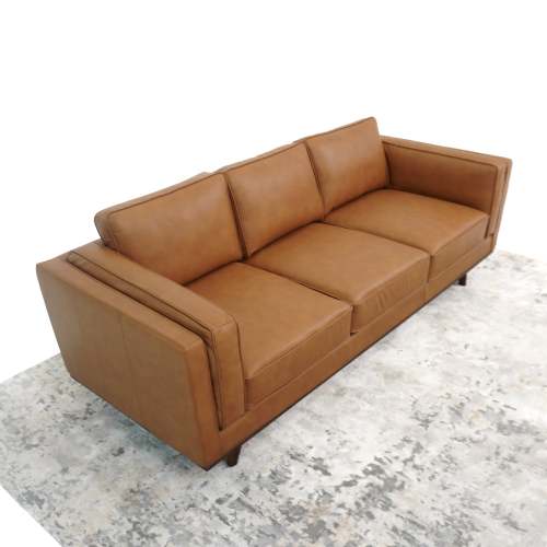 The Ashcroft Furniture Chase MCM Genuine Leather Sofa 91 is a modern brown three-seater with square arms and back cushions, adding luxury to any room atop a light-patterned rug against a white backdrop.