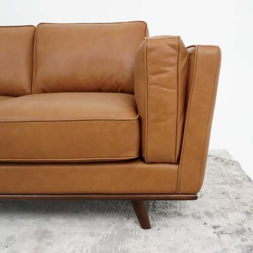 A close-up of the right side of the Ashcroft Furniture Chase MCM Genuine Leather Sofa 91 with wooden legs, set on a light textured rug against a white background, highlights its mid-century modern luxury.