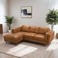 A modern living room with the Ashcroft Furniture Chase MCM Tan Leather Chaise Sofa Sectional 92 on a light rug, surrounded by large potted plants, abstract wall art, and sheer white curtains letting in natural light.