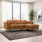 A modern living room features the Ashcroft Furniture Chase MCM Tan Leather Chaise Sofa Sectional 92 on a patterned rug, paired with large windows, white curtains, a tall plant, and a black-and-white framed photo for mid-century modern style.