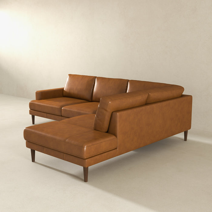 The Ashcroft Furniture Corbin MCM Tan Leather Sectional Chaise Sofa 108 features a modern L-shaped design with wooden legs, perfect for minimalistic rooms with light walls and floors, highlighting subtle mid-century modern style.