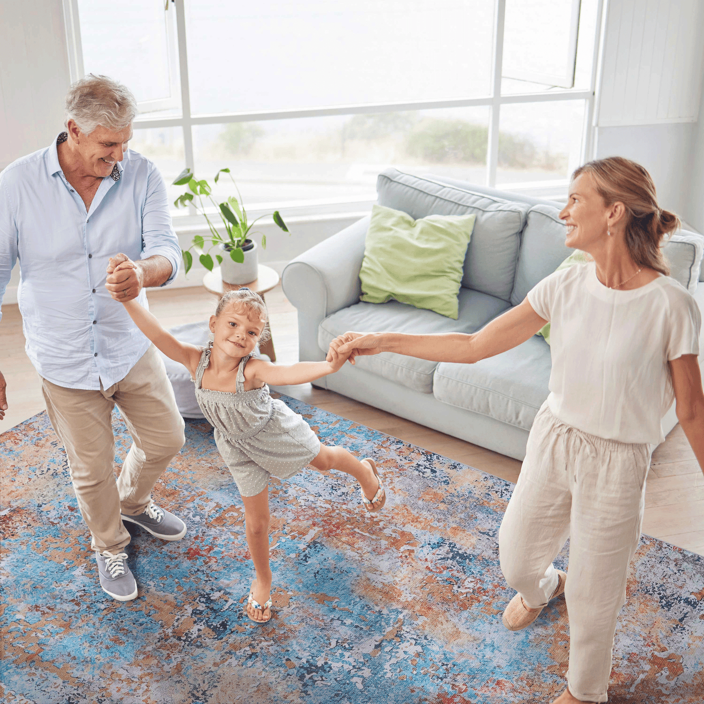 Family dancing together on a vibrant multi-colored abstract area rug in a cozy living room.