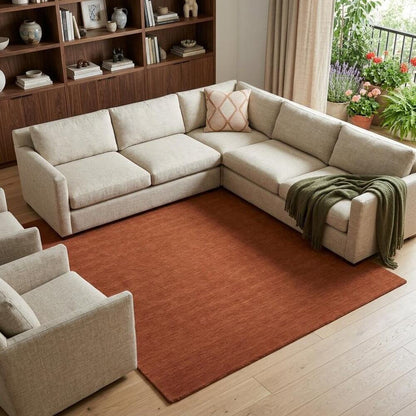Orange Wool Hand Woven Area Rug | 9' x 13' placed beneath a light-colored sectional sofa in a cozy living room.