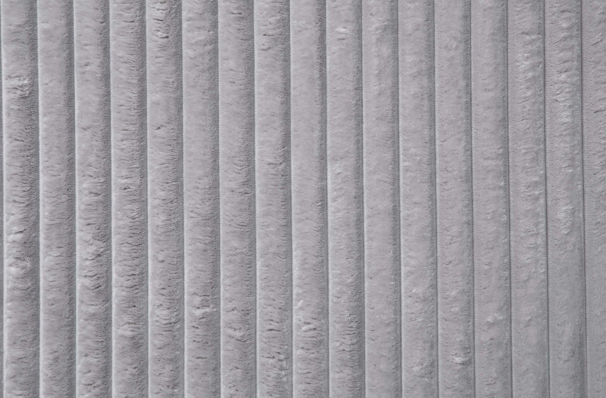 Close-up of gray corduroy fabric texture showcasing vertical ridges and plush softness.