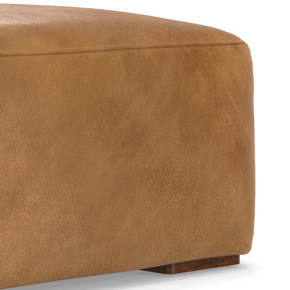 Close-up of Rex Genuine Leather Square Ottoman in tan, showcasing its smooth texture and sturdy wooden base.