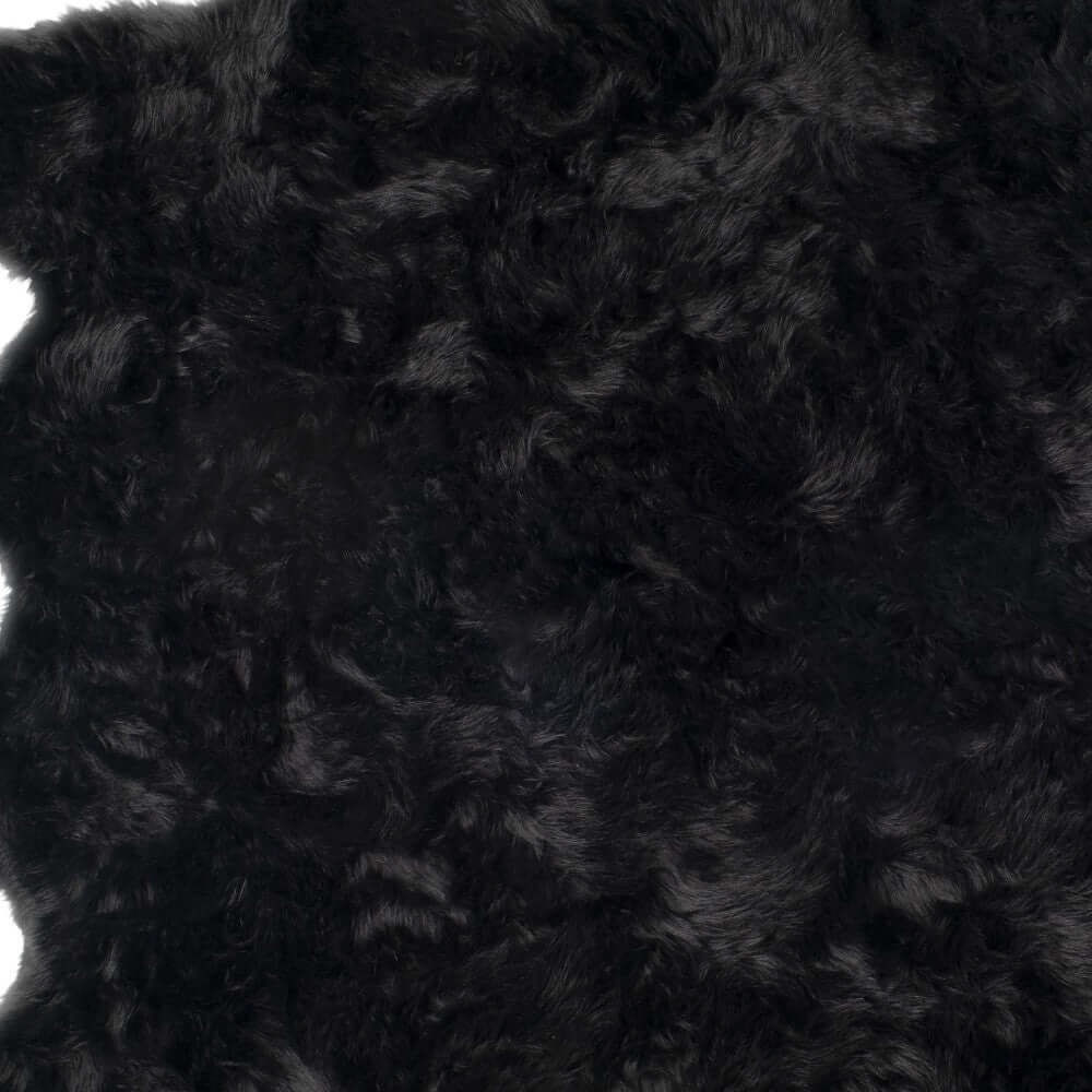 Close-up of soft black faux fur shag rug, showcasing plush texture and scalloped design ideal for modern decor.