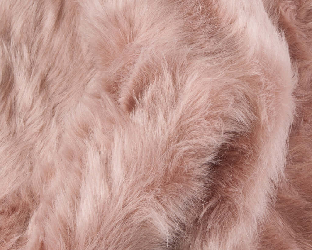 Close-up of soft pink faux fur fabric, showcasing plush texture and luxurious feel, ideal for home decor.